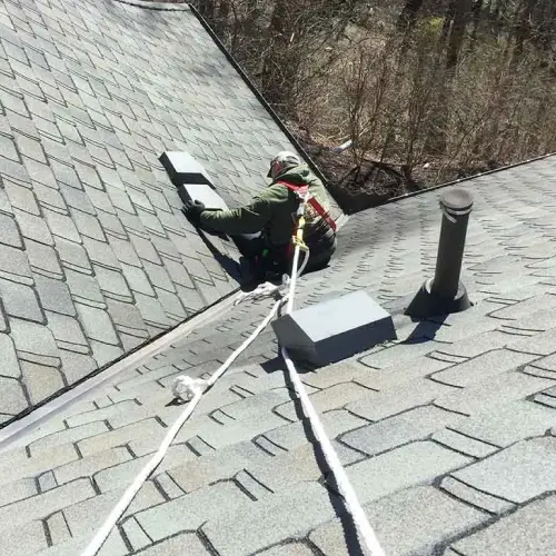 A Barnes Wildlife Control technician repairs a damaged vent on the roof of a home from wildlife intrusion